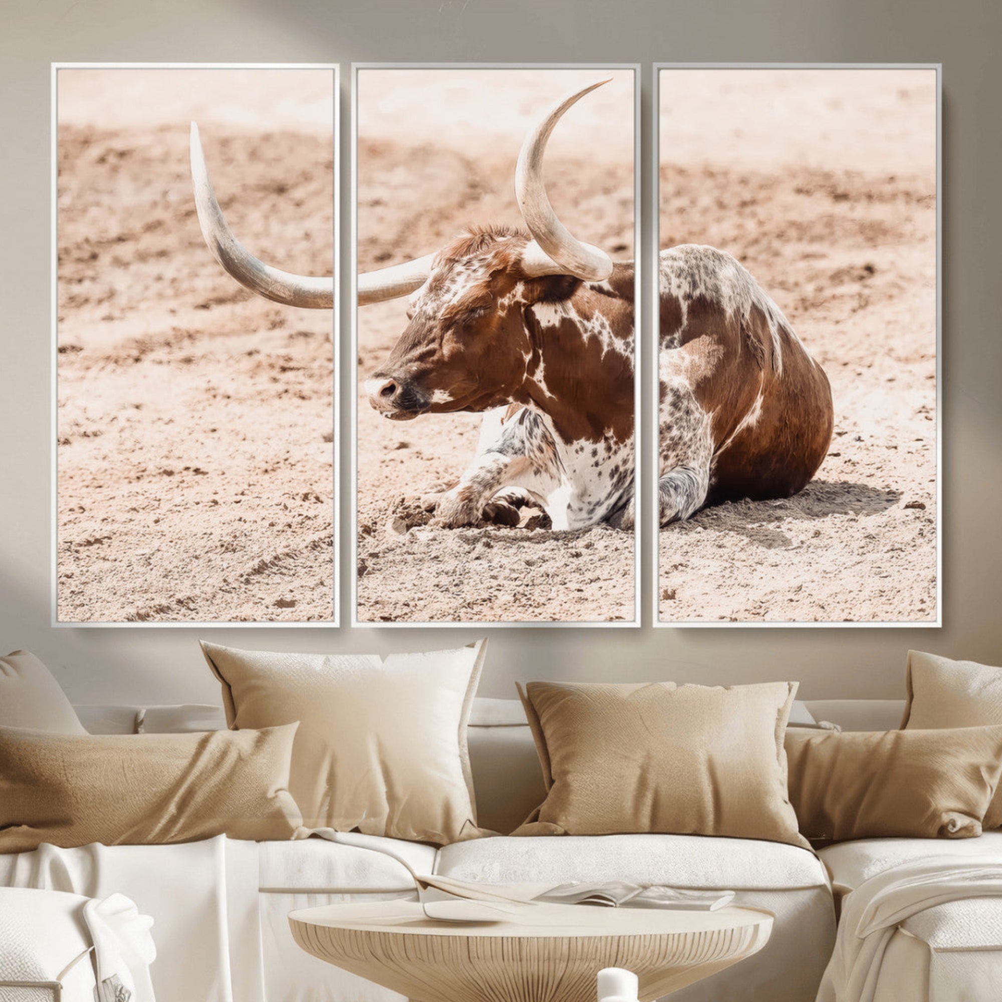 Texas Longhorn bull resting on dusty ground with warm tones, ideal for rustic western or farmhouse-themed wall decor.