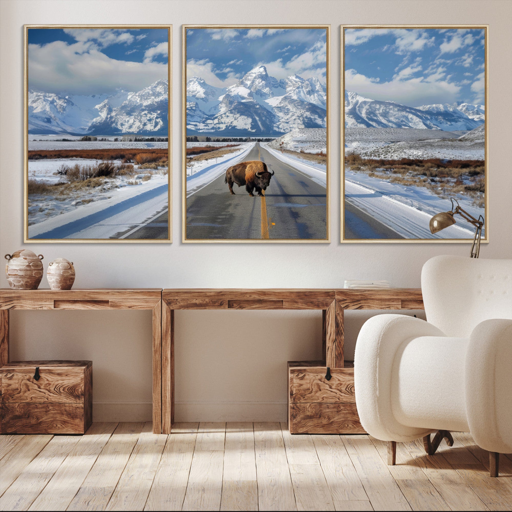 A powerful bison stands on a snow-dusted road beneath the towering peaks of the Grand Tetons, capturing the untamed beauty of America's winter wilderness.