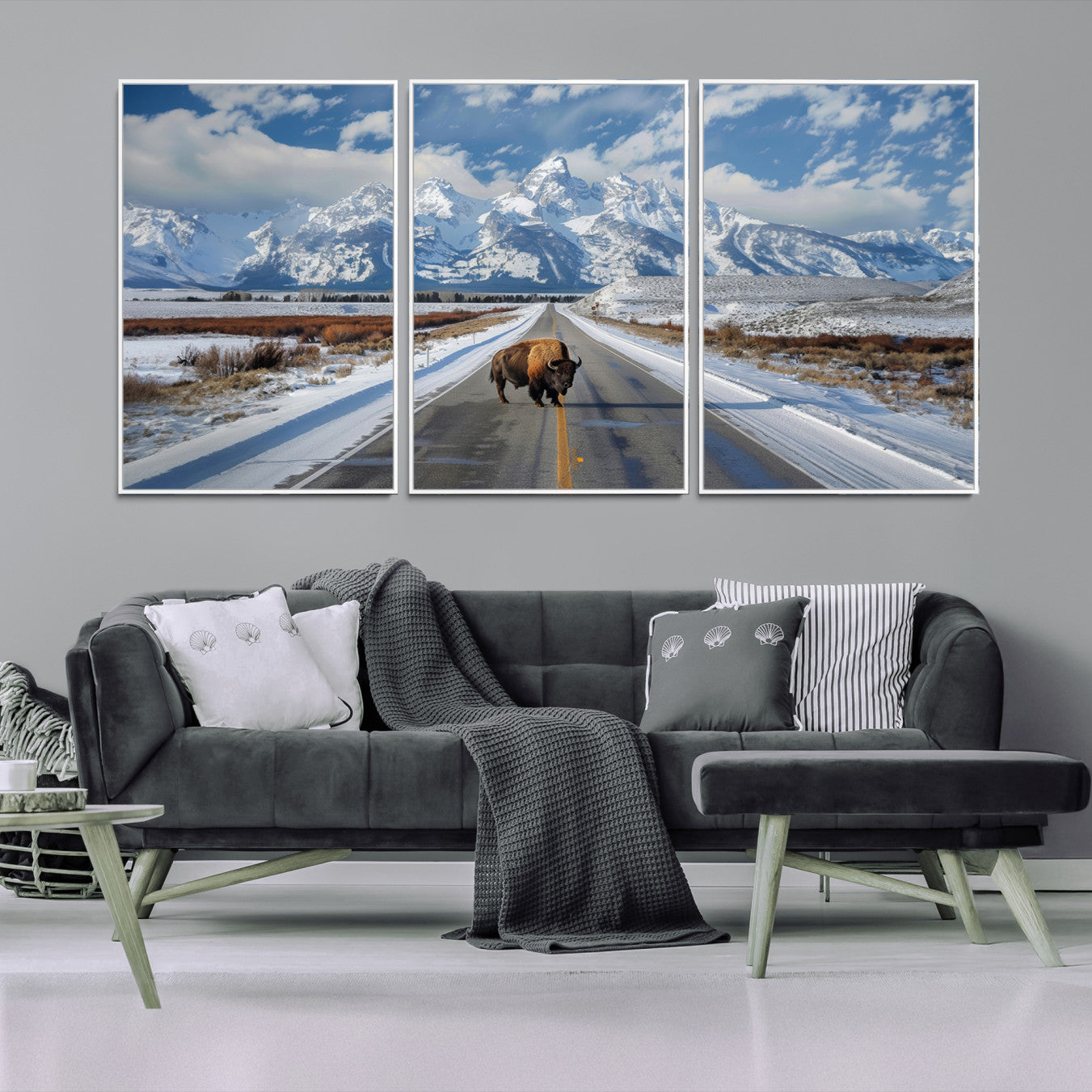 A powerful bison stands on a snow-dusted road beneath the towering peaks of the Grand Tetons, capturing the untamed beauty of America's winter wilderness.