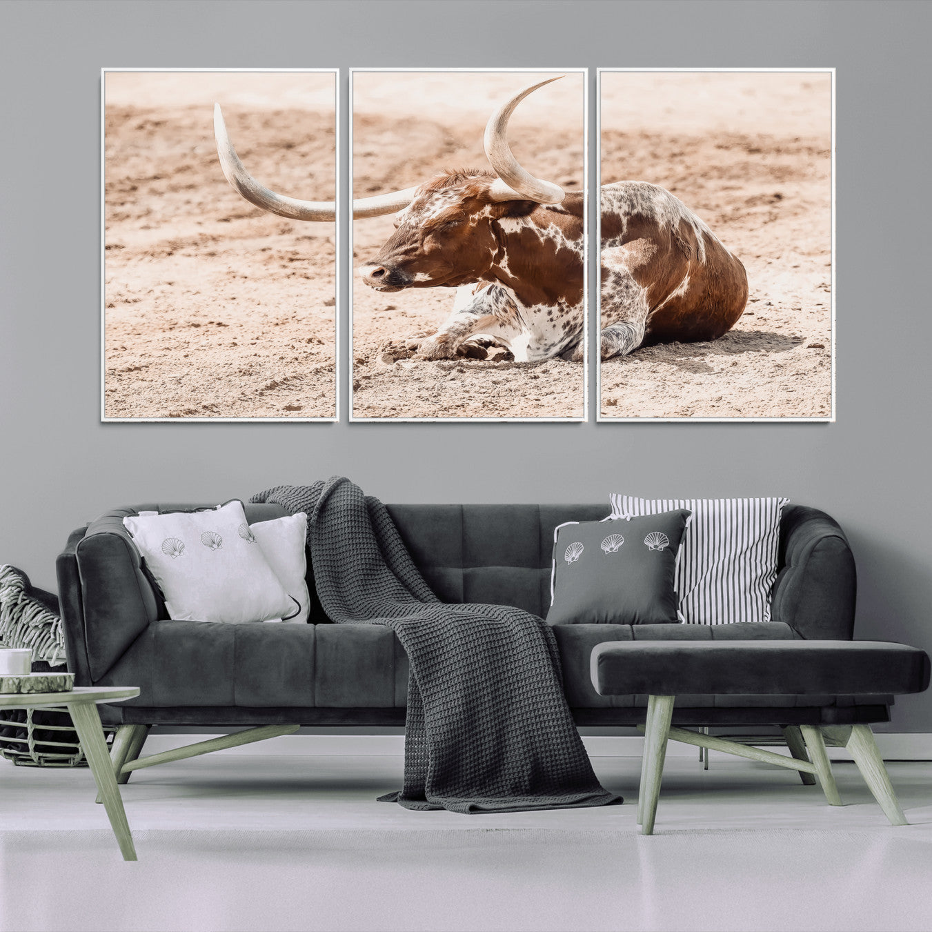 Texas Longhorn bull resting on dusty ground with warm tones, ideal for rustic western or farmhouse-themed wall decor.