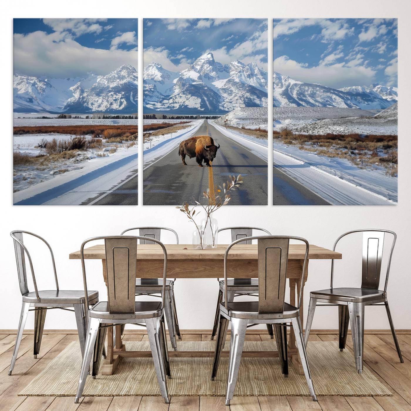 A powerful bison stands on a snow-dusted road beneath the towering peaks of the Grand Tetons, capturing the untamed beauty of America's winter wilderness.