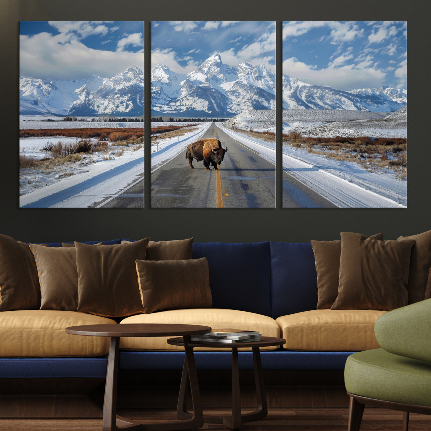 A powerful bison stands on a snow-dusted road beneath the towering peaks of the Grand Tetons, capturing the untamed beauty of America's winter wilderness.