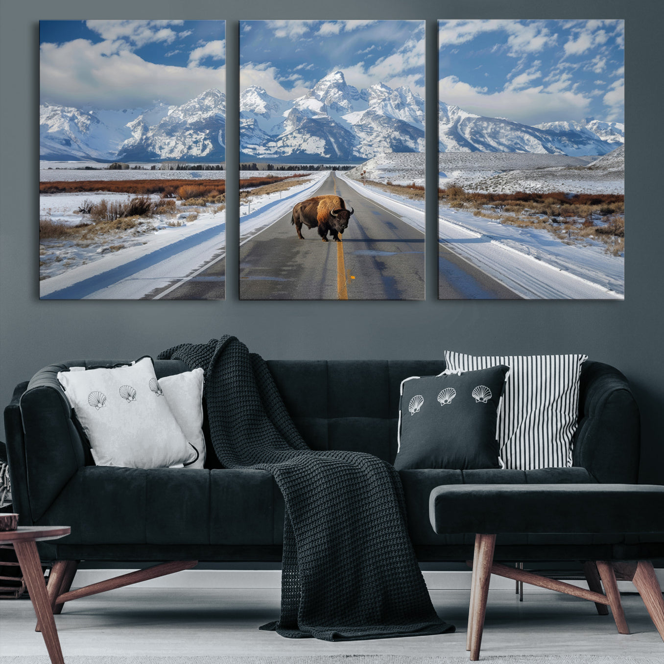 A powerful bison stands on a snow-dusted road beneath the towering peaks of the Grand Tetons, capturing the untamed beauty of America's winter wilderness.