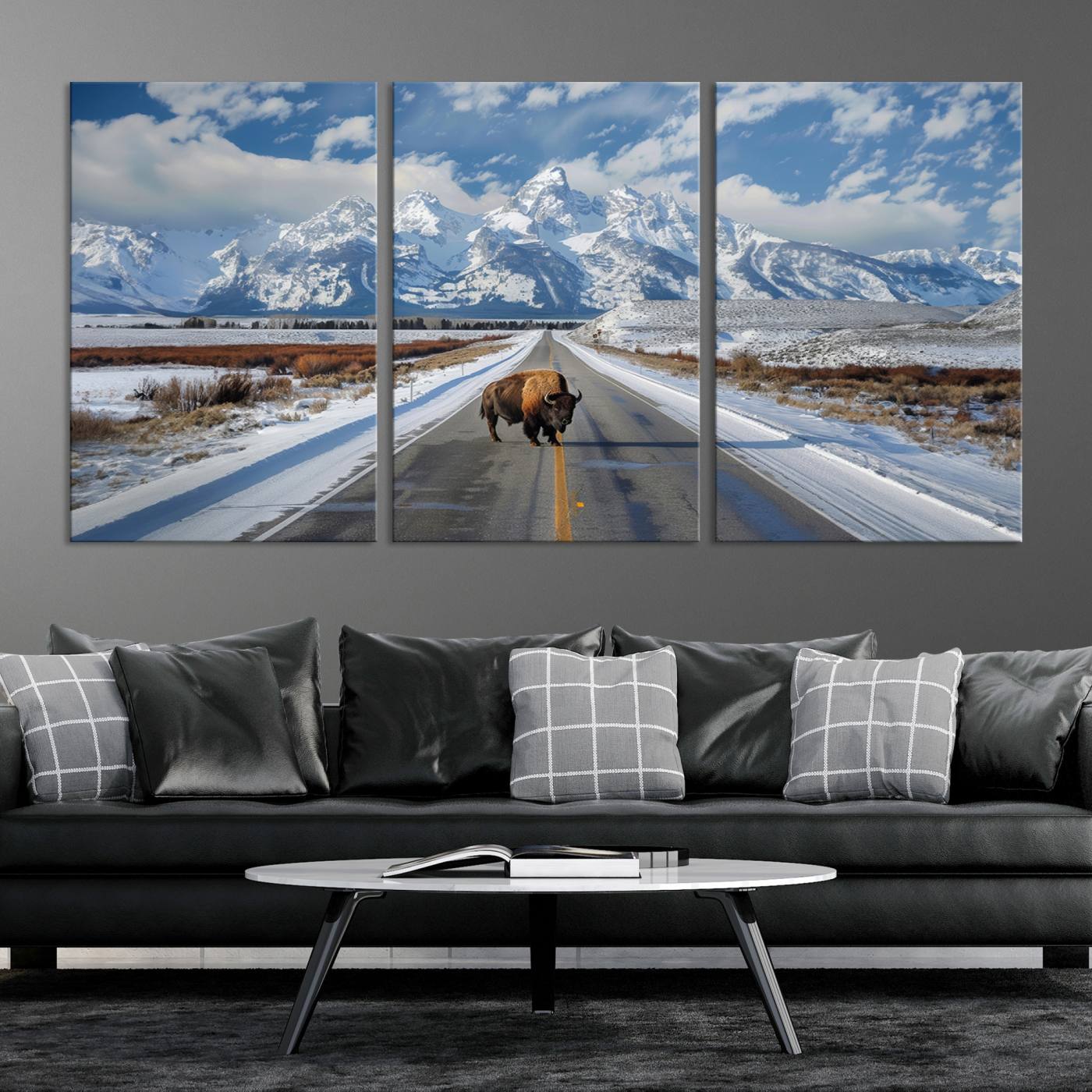 A powerful bison stands on a snow-dusted road beneath the towering peaks of the Grand Tetons, capturing the untamed beauty of America's winter wilderness.
