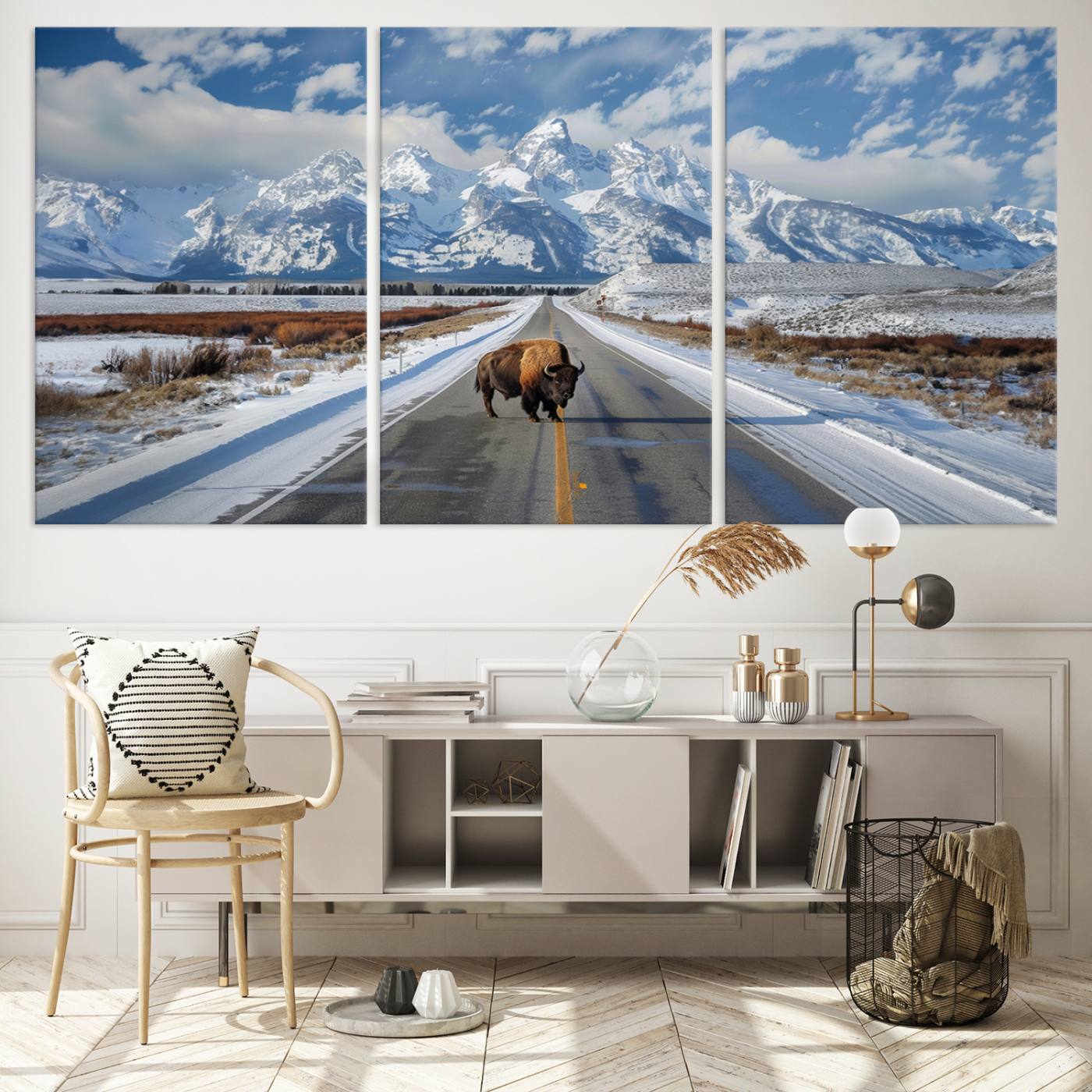A powerful bison stands on a snow-dusted road beneath the towering peaks of the Grand Tetons, capturing the untamed beauty of America's winter wilderness.