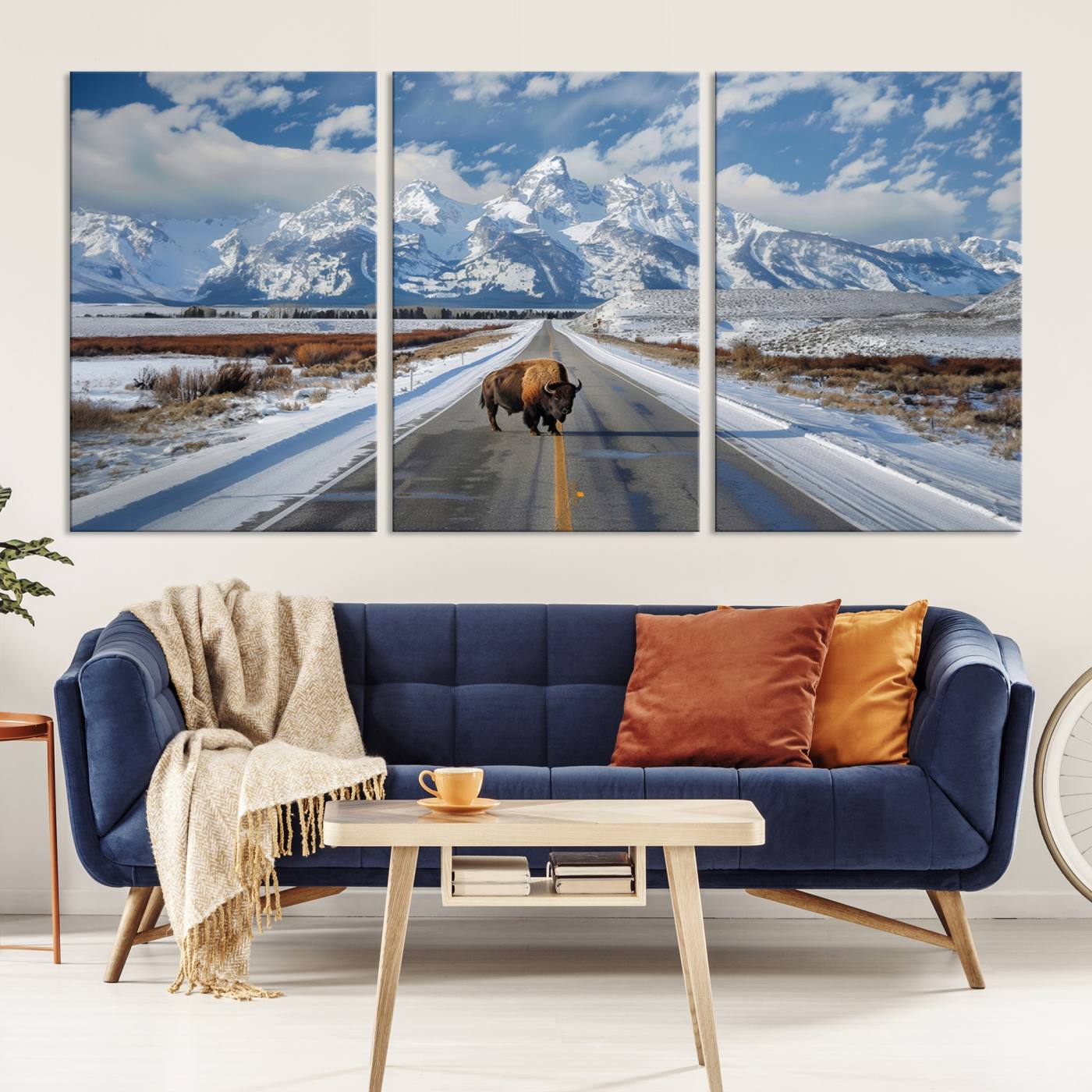 A powerful bison stands on a snow-dusted road beneath the towering peaks of the Grand Tetons, capturing the untamed beauty of America's winter wilderness.