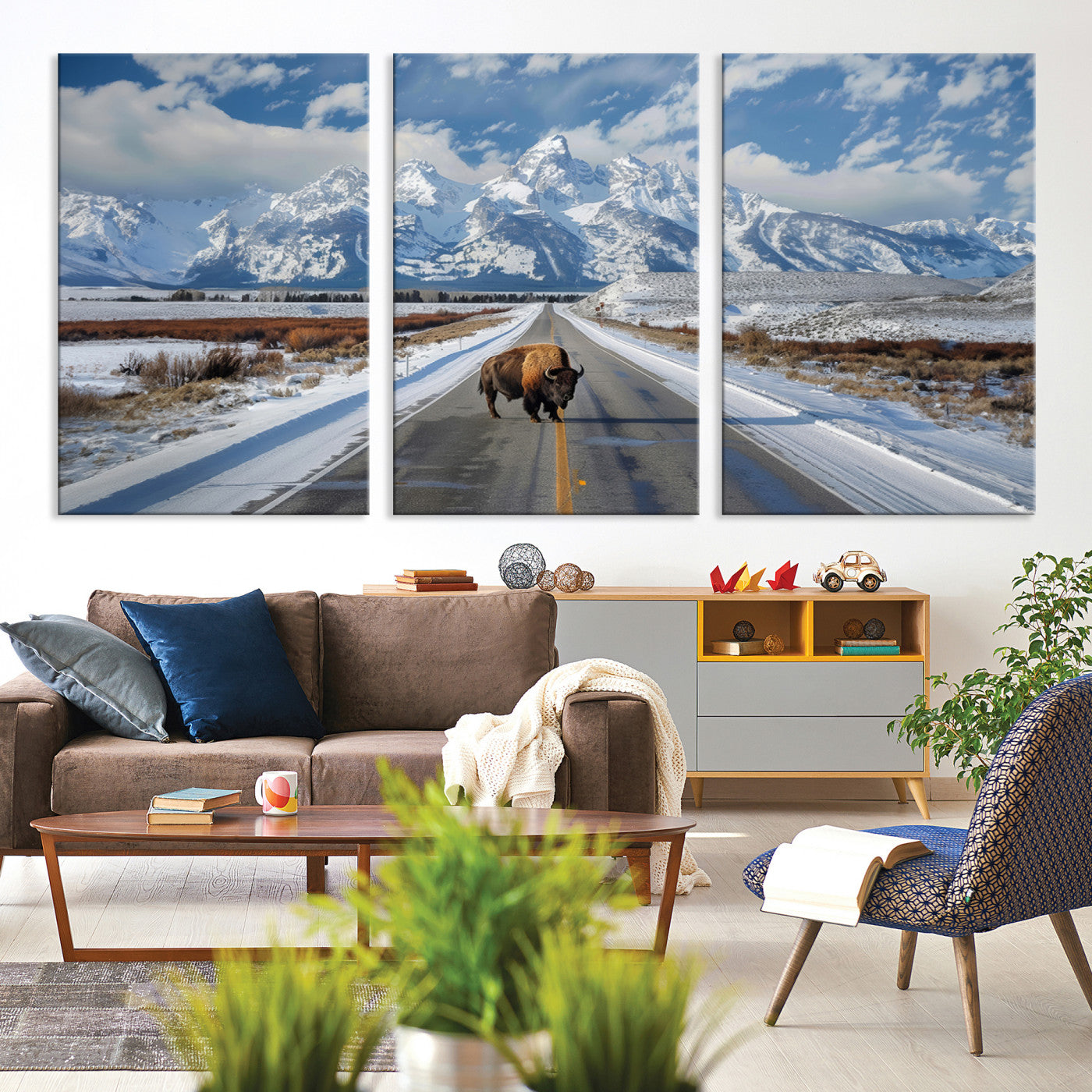 A powerful bison stands on a snow-dusted road beneath the towering peaks of the Grand Tetons, capturing the untamed beauty of America's winter wilderness.