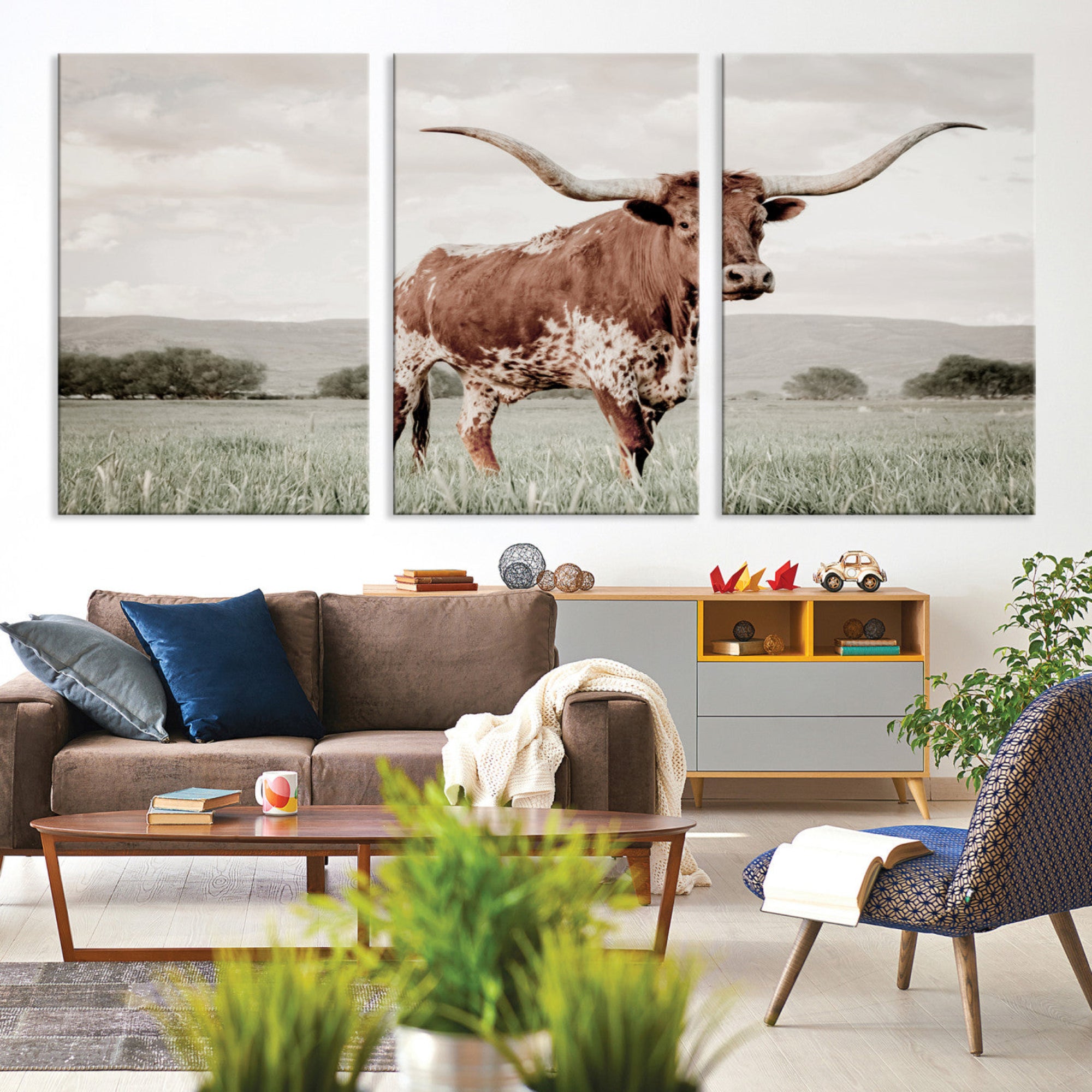 Canvas of a Texas longhorn standing in a grassy field with mountains in the background, ideal for rustic or country-style western wall decor.