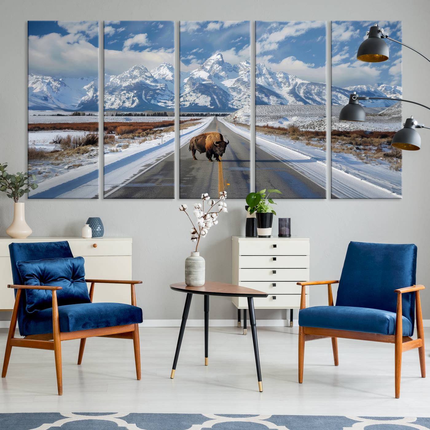A powerful bison stands on a snow-dusted road beneath the towering peaks of the Grand Tetons, capturing the untamed beauty of America's winter wilderness.