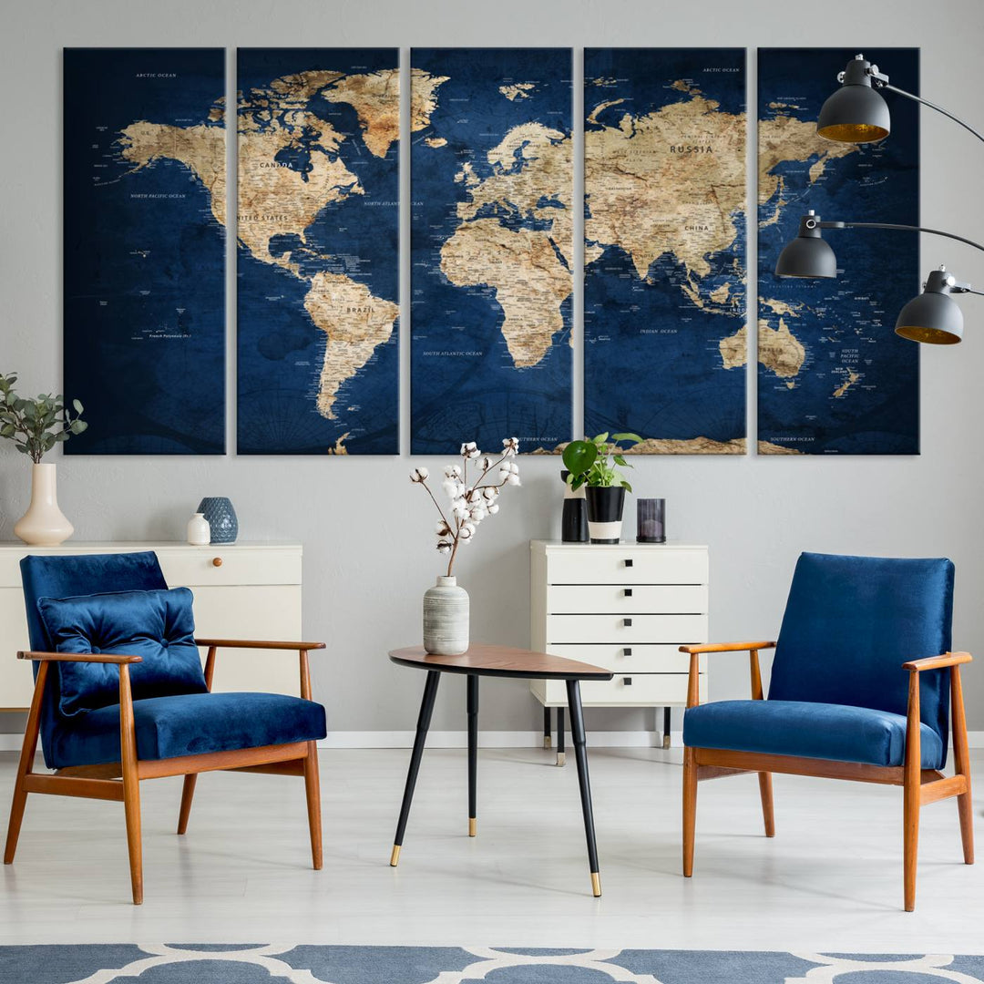 A large framed world map canvas print features beige landmasses set against a grunge-stained deep blue ocean background, creating an intriguing piece of wall art.