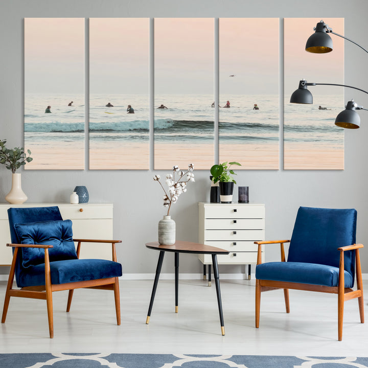 Dreamy photo of surfers waiting on soft pastel waves under a pink sunset sky, ideal for soft coastal minimalist or serene ocean-themed home decor.
