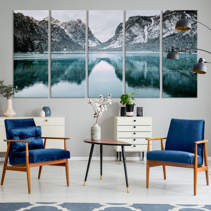 Crystal-clear alpine lake reflecting snow-covered mountains, surrounded by evergreen trees, creating a serene and tranquil winter landscape.