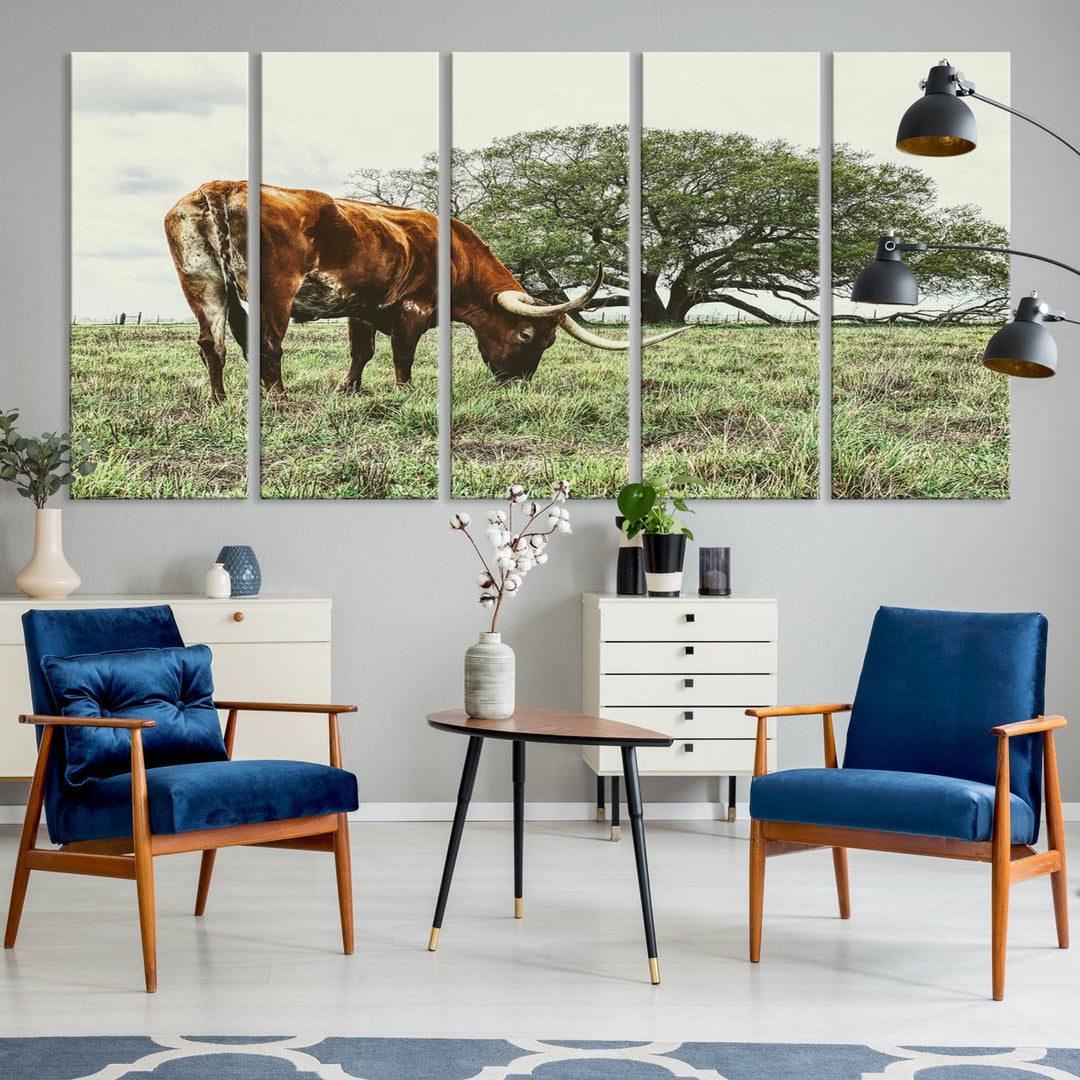 A Texas Longhorn grazing in a green pasture with a large tree in the background, evoking a rustic Western and farmhouse aesthetic.