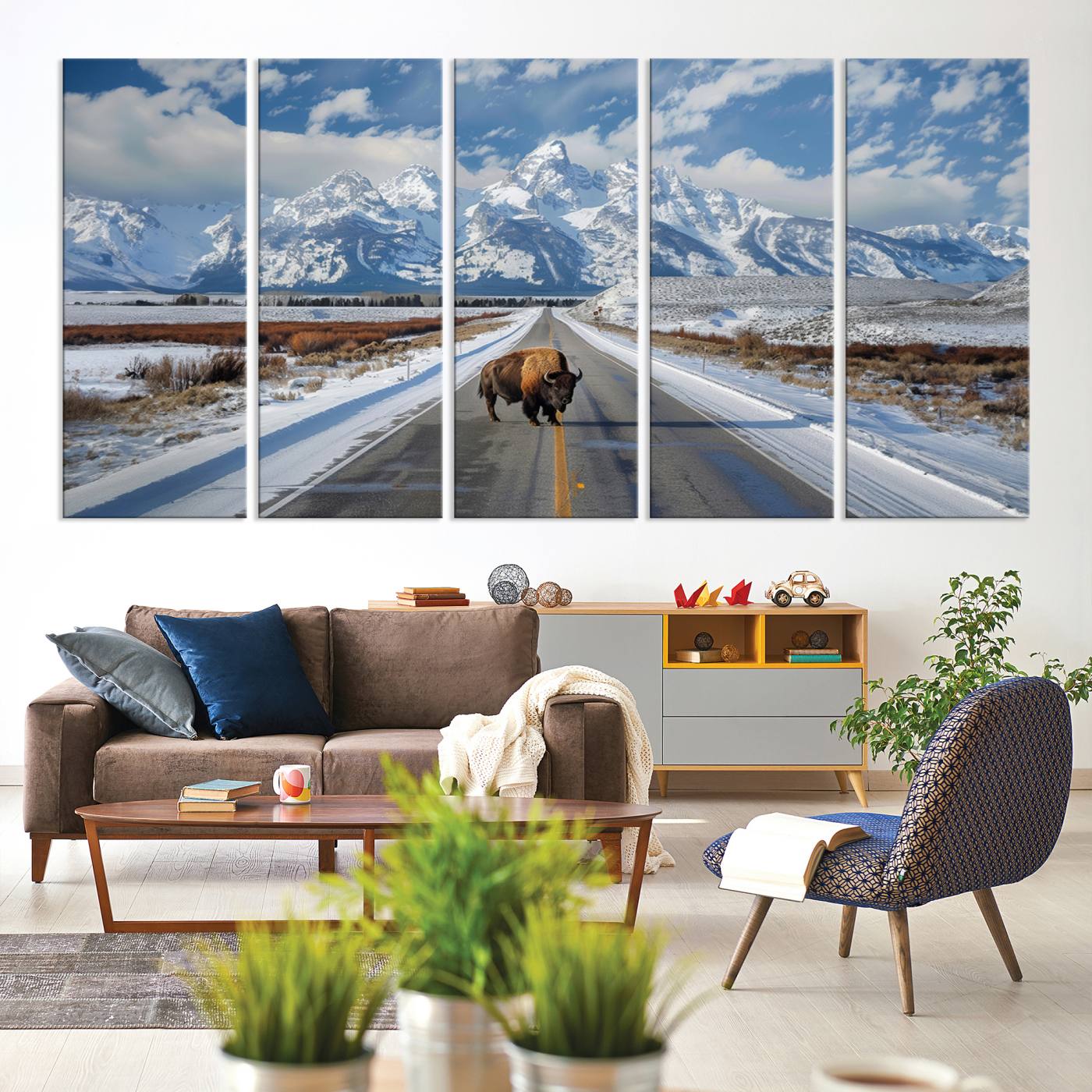 A powerful bison stands on a snow-dusted road beneath the towering peaks of the Grand Tetons, capturing the untamed beauty of America's winter wilderness.