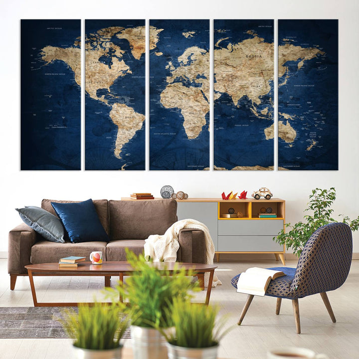 A large framed world map canvas print features beige landmasses set against a grunge-stained deep blue ocean background, creating an intriguing piece of wall art.