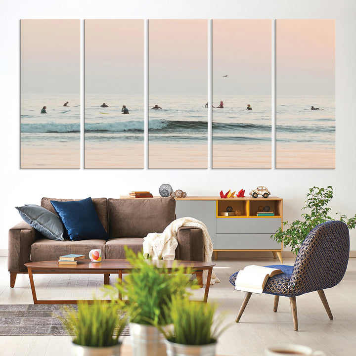 Dreamy photo of surfers waiting on soft pastel waves under a pink sunset sky, ideal for soft coastal minimalist or serene ocean-themed home decor.