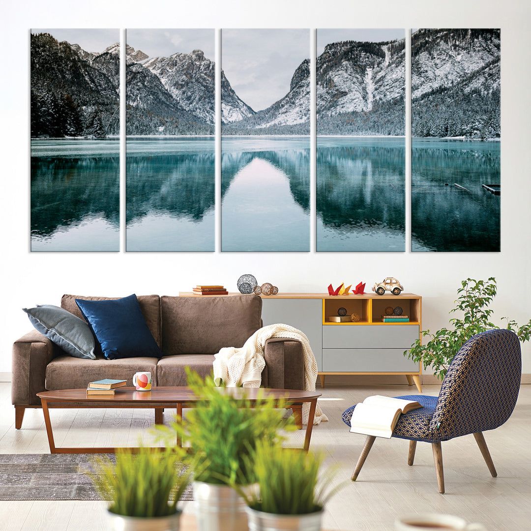 Crystal-clear alpine lake reflecting snow-covered mountains, surrounded by evergreen trees, creating a serene and tranquil winter landscape.