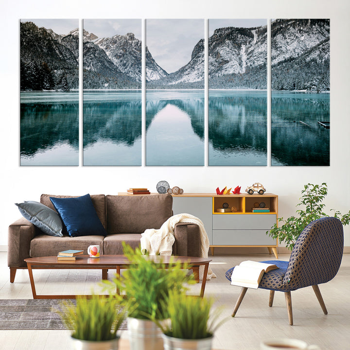 Crystal-clear alpine lake reflecting snow-covered mountains, surrounded by evergreen trees, creating a serene and tranquil winter landscape.