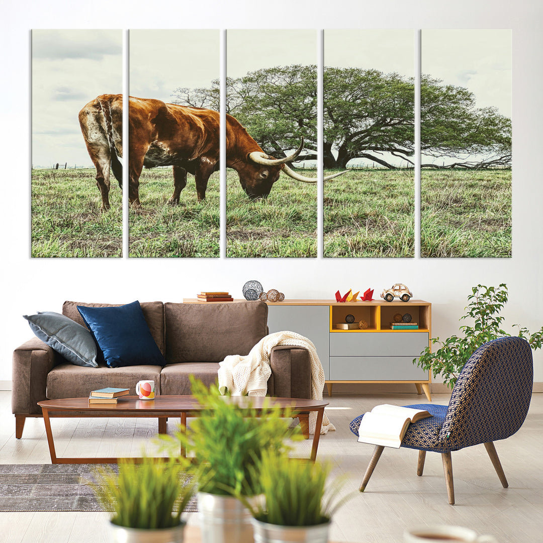 A Texas Longhorn grazing in a green pasture with a large tree in the background, evoking a rustic Western and farmhouse aesthetic.