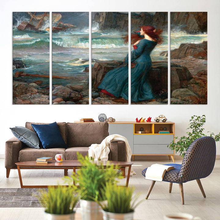 The Miranda by the Shore Wall Art Canvas Print depicts a woman in a blue dress standing by the sea, watching a shipwreck.