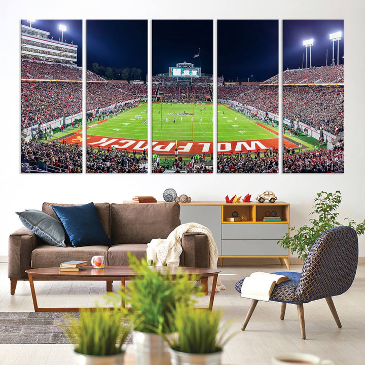 A NC State Wolfpack Football Team print of Carter-Finley Stadium at night features WOLFPACK illuminated brightly in the end zone grass.