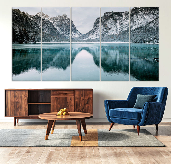 Crystal-clear alpine lake reflecting snow-covered mountains, surrounded by evergreen trees, creating a serene and tranquil winter landscape.