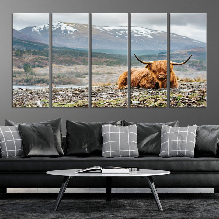 Highland Cow Horn Farm Wall Art Canvas Print is displayed against a wooden wall featuring a mountainous backdrop.