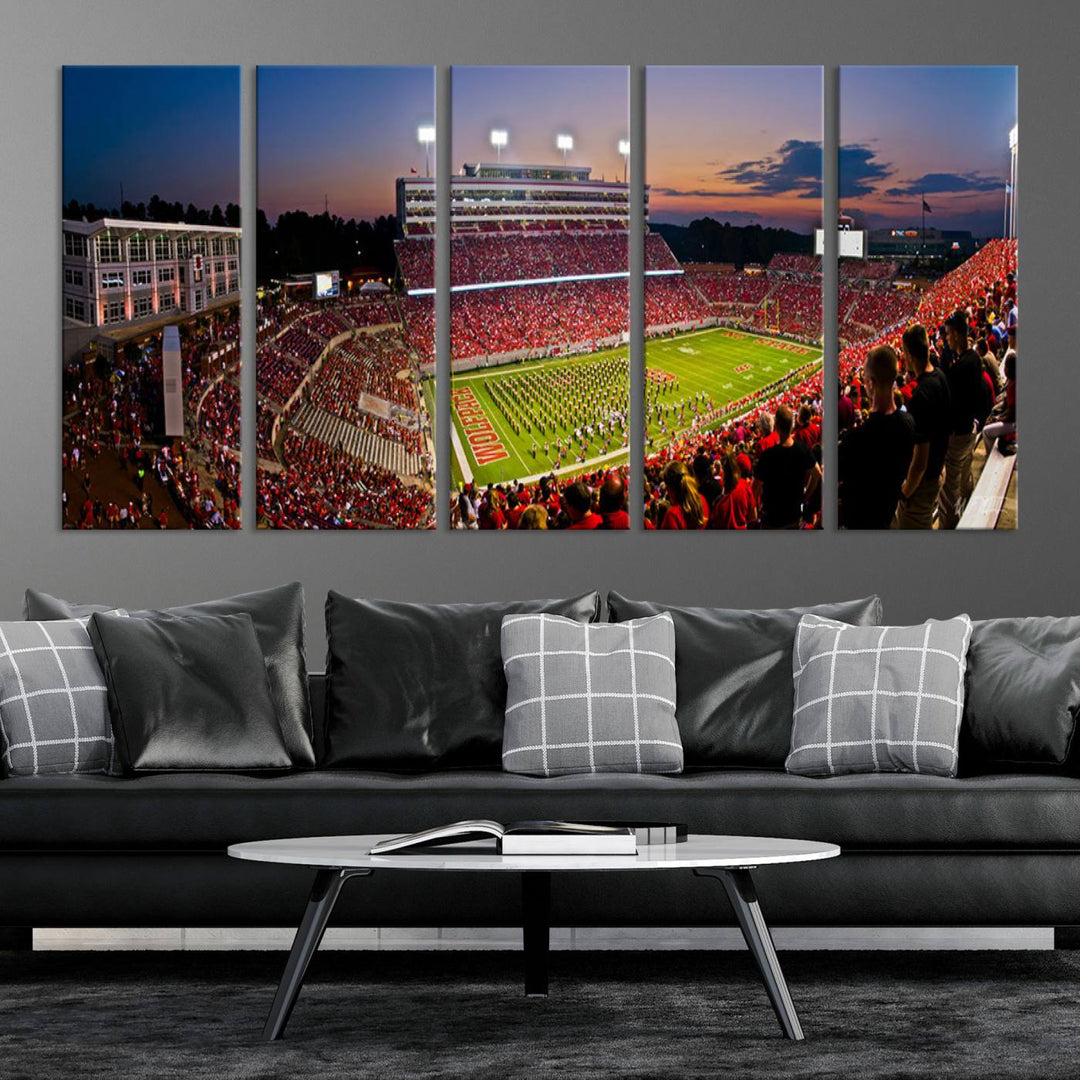 A print of a bustling Carter-Finley Stadium at dusk, featuring fans and a band, captures the essence of NC State Wolfpack football.