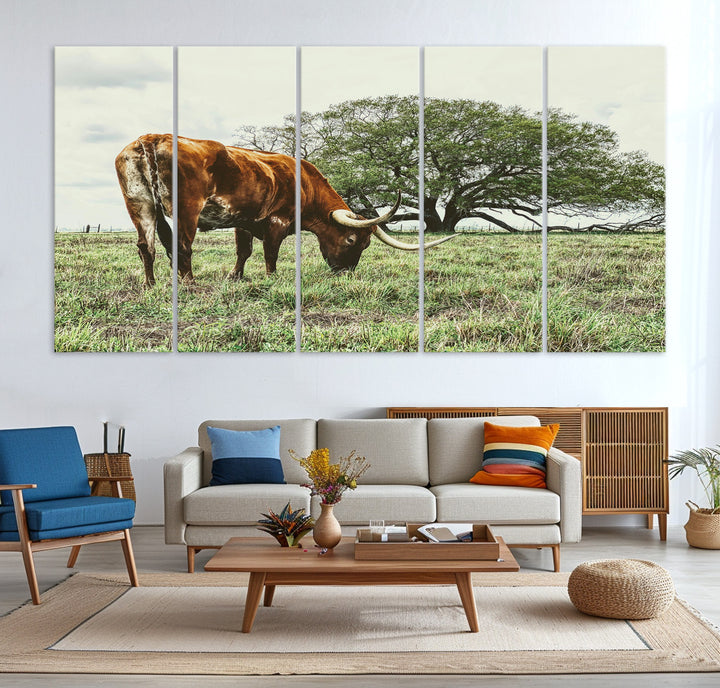 A Texas Longhorn grazing in a green pasture with a large tree in the background, evoking a rustic Western and farmhouse aesthetic.