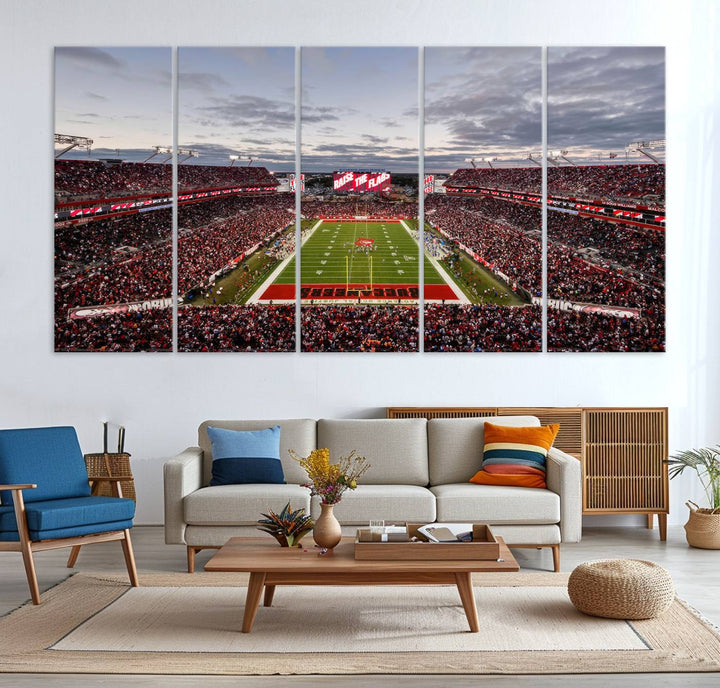 The wall art captures a stunning scene of Raymond James Stadium bathed in the warm hues of sunset. The sky, filled with clouds, provides a dramatic contrast to the vibrant lighting on the field, encapsulating the dynamic energy of a football game.