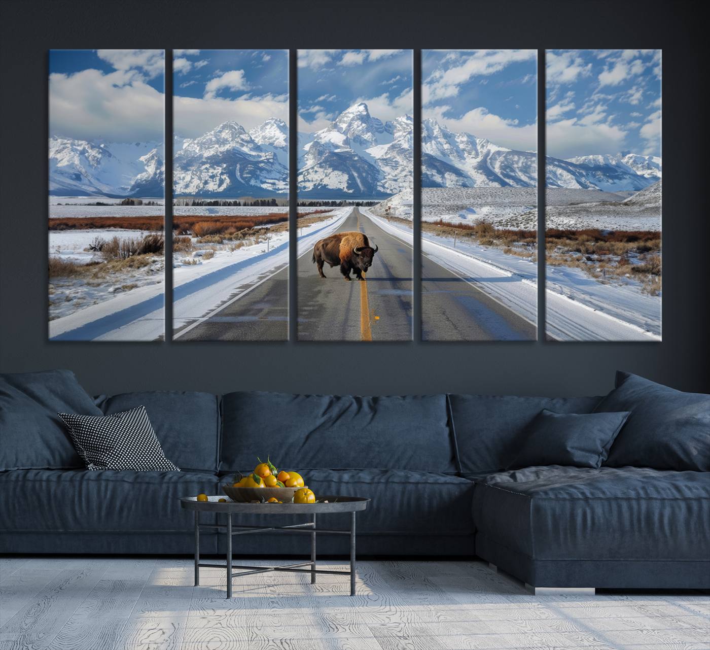 A powerful bison stands on a snow-dusted road beneath the towering peaks of the Grand Tetons, capturing the untamed beauty of America's winter wilderness.