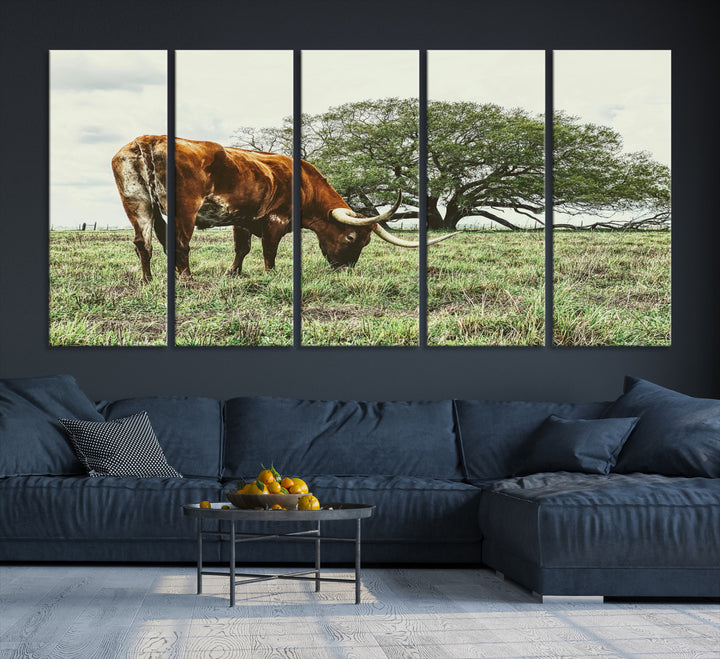 A Texas Longhorn grazing in a green pasture with a large tree in the background, evoking a rustic Western and farmhouse aesthetic.