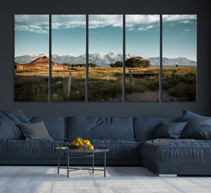 A rustic farmhouse with a wooden barn set against majestic mountain peaks under a soft blue sky, evoking peaceful countryside charm.