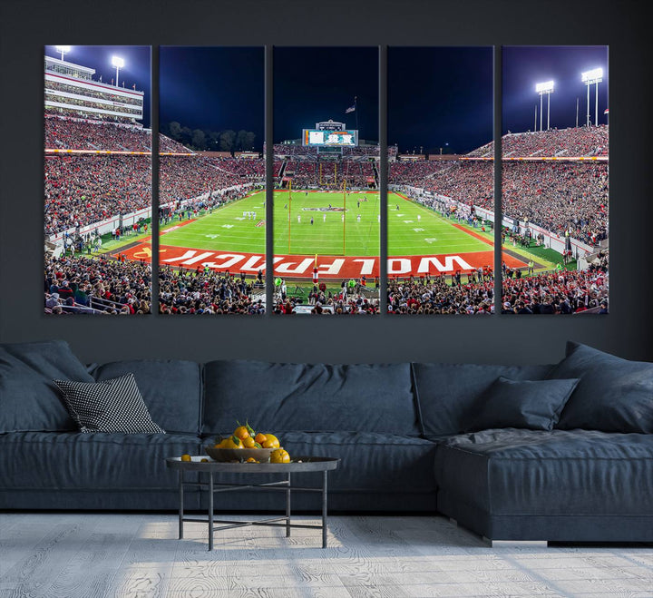 A NC State Wolfpack Football Team print of Carter-Finley Stadium at night features WOLFPACK illuminated brightly in the end zone grass.