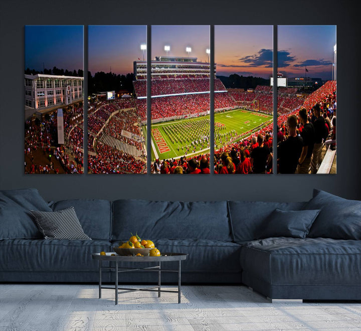 A print of a bustling Carter-Finley Stadium at dusk, featuring fans and a band, captures the essence of NC State Wolfpack football.