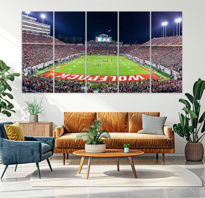 A NC State Wolfpack Football Team print of Carter-Finley Stadium at night features WOLFPACK illuminated brightly in the end zone grass.