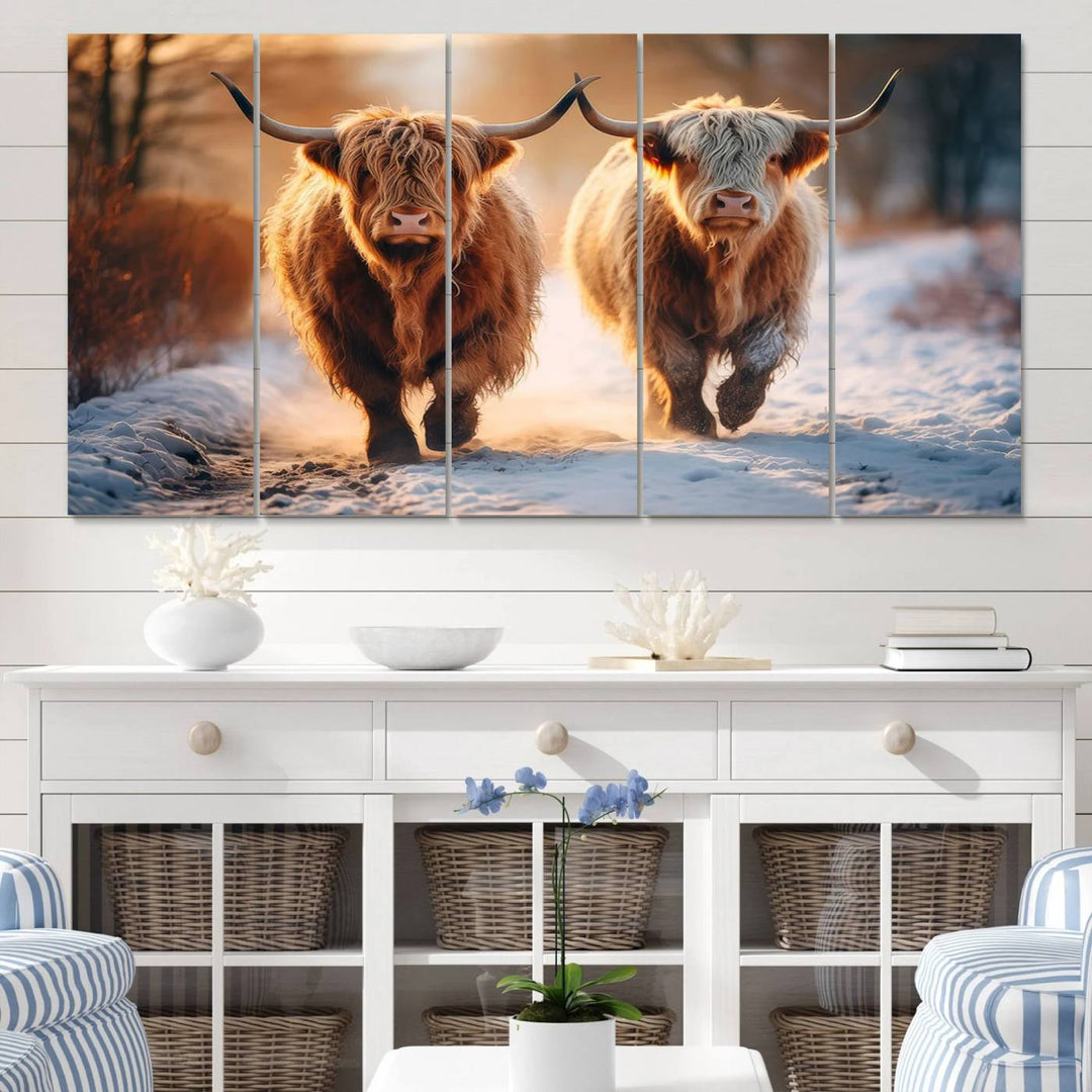 The wall art is a Scottish Highland Cow Horn canvas print featuring cows on a snowy path bathed in warm sunlight, serving as a rustic decor piece.