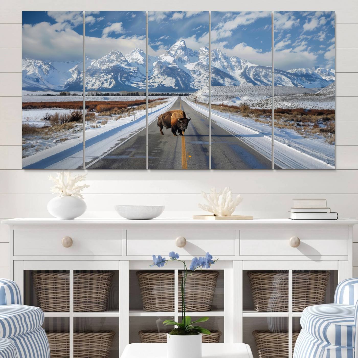 A powerful bison stands on a snow-dusted road beneath the towering peaks of the Grand Tetons, capturing the untamed beauty of America's winter wilderness.