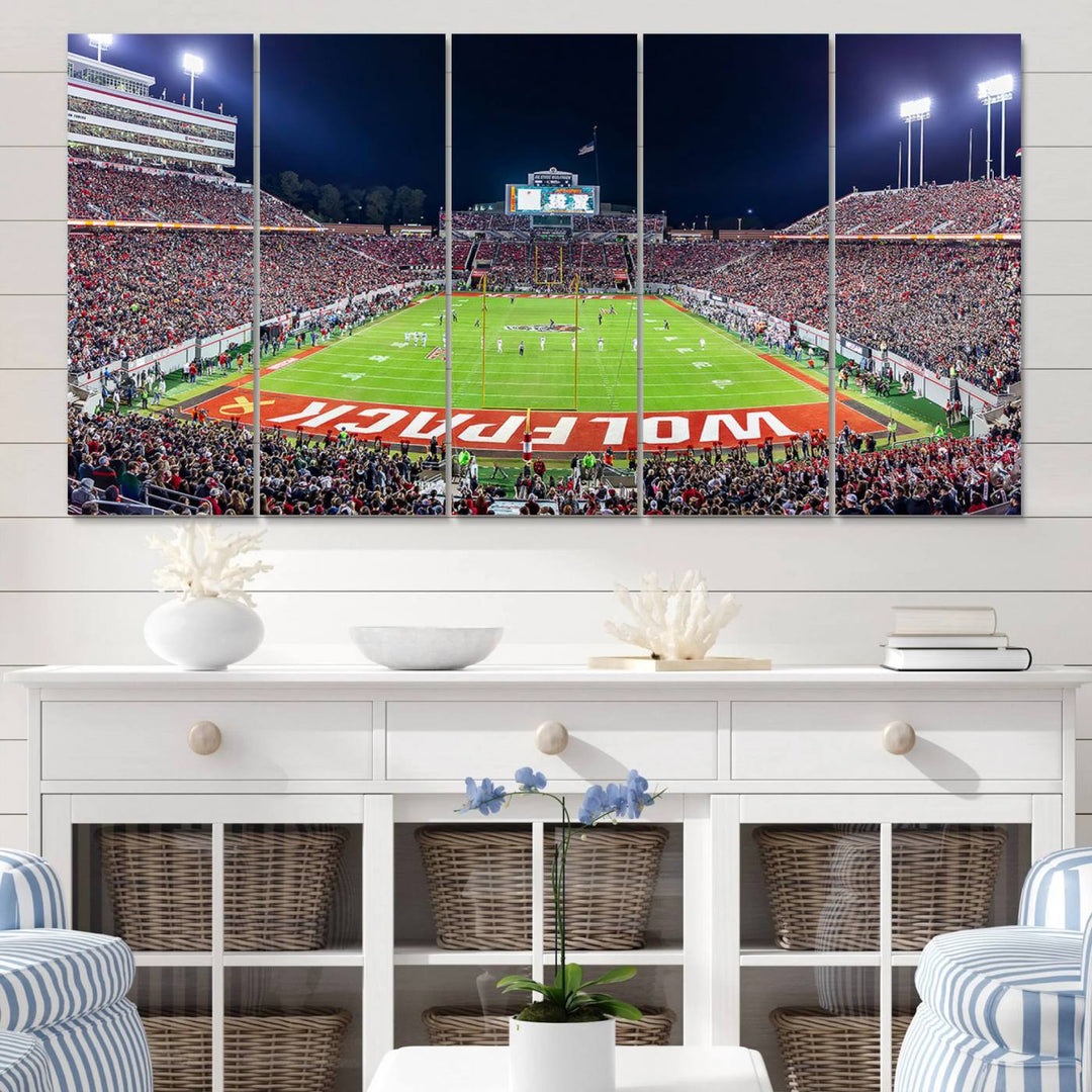 A NC State Wolfpack Football Team print of Carter-Finley Stadium at night features WOLFPACK illuminated brightly in the end zone grass.