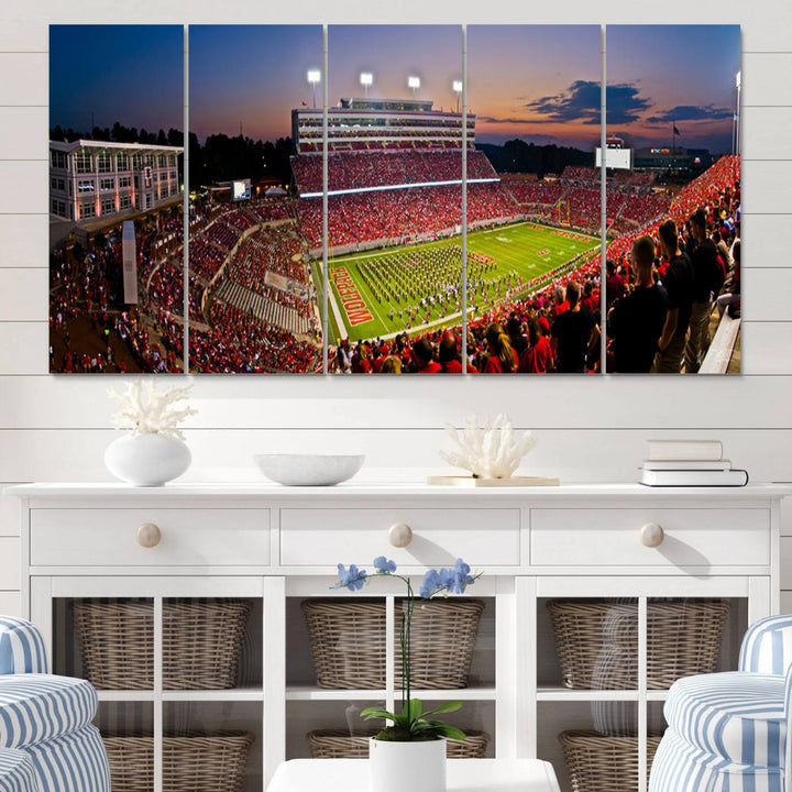 A print of a bustling Carter-Finley Stadium at dusk, featuring fans and a band, captures the essence of NC State Wolfpack football.