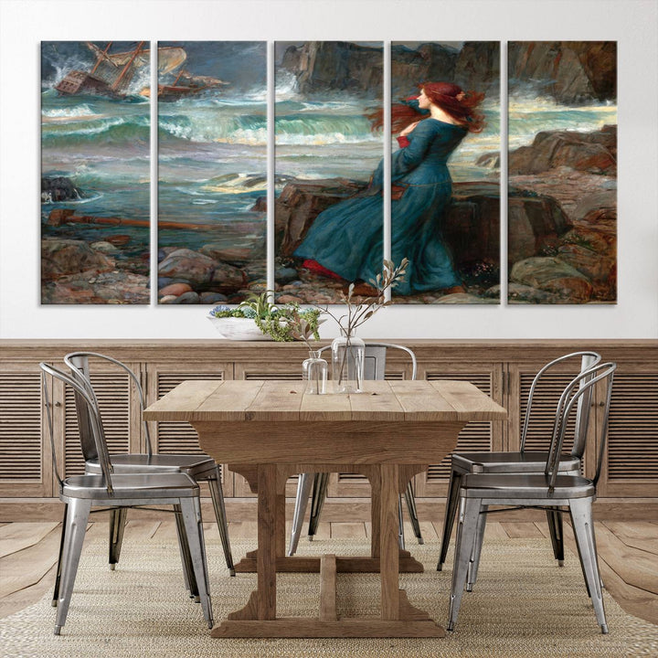 The Miranda by the Shore Wall Art Canvas Print depicts a woman in a blue dress standing by the sea, watching a shipwreck.