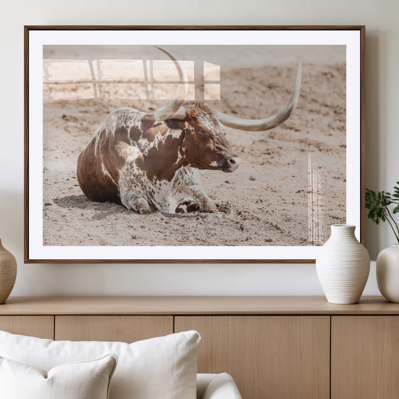 Texas Longhorn bull resting on dusty ground with warm tones, ideal for rustic western or farmhouse-themed wall decor.