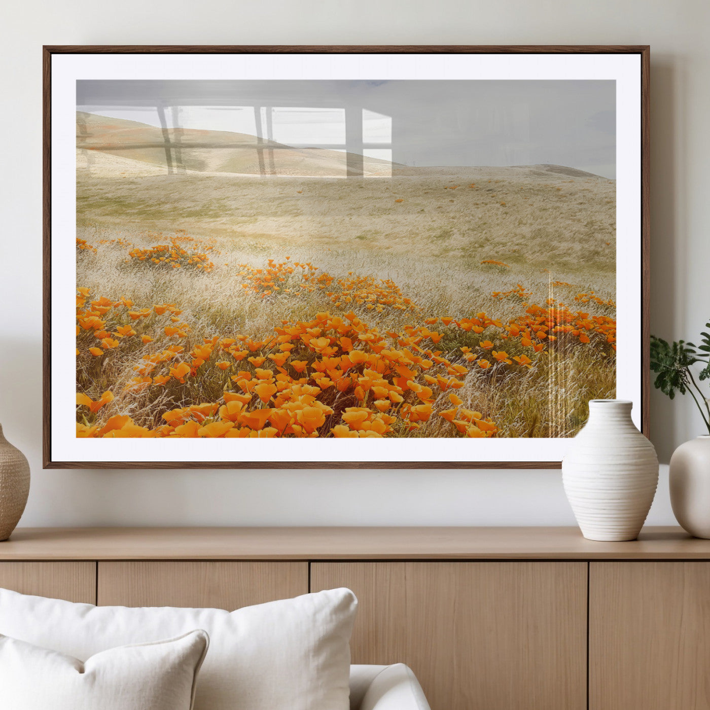 A golden field with vibrant orange poppies blooming across rolling hills under a soft, sunlit sky, creating a warm and rustic landscape.