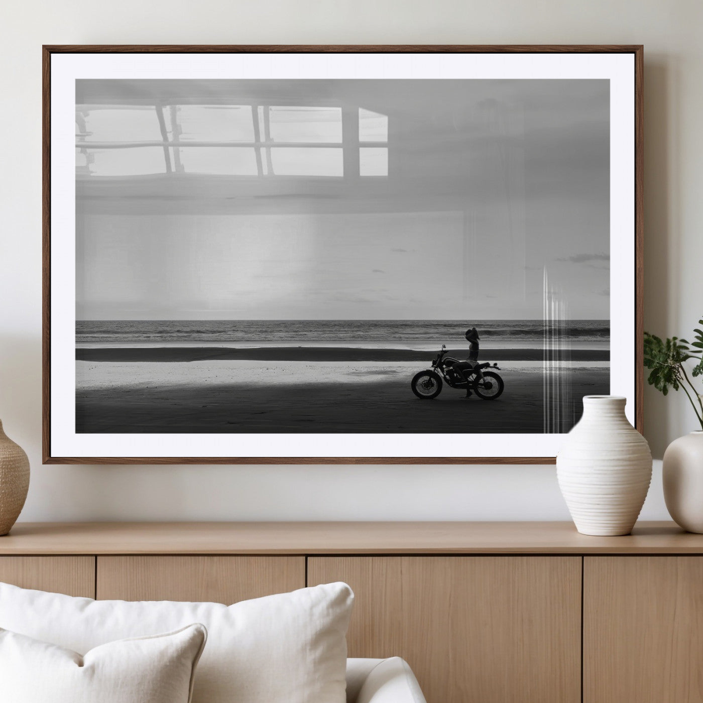 A motorcyclist on a vast beach, gazing at the ocean, capturing a moody and tranquil coastal adventure in black and white.