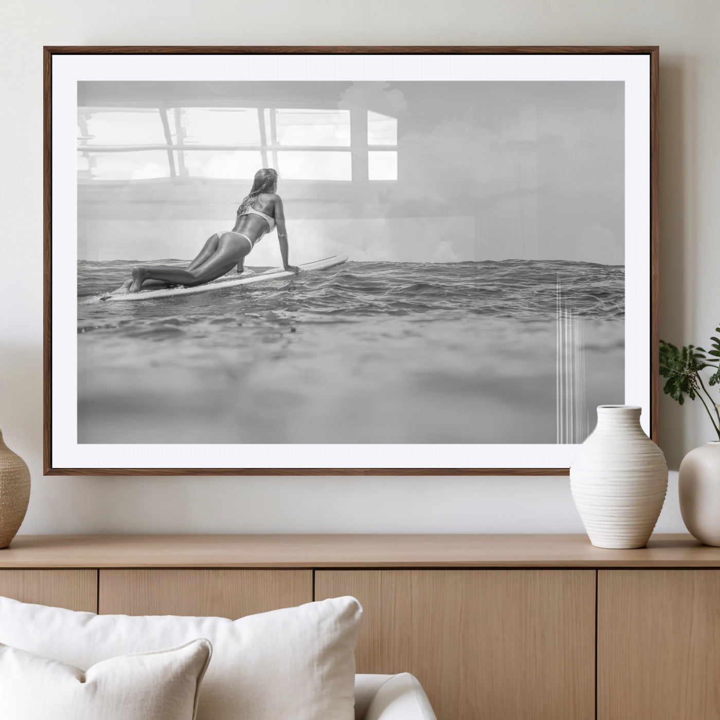 A black and white ocean scene featuring a surfer girl waiting on her board, gazing at the horizon, capturing a tranquil and adventurous coastal moment.