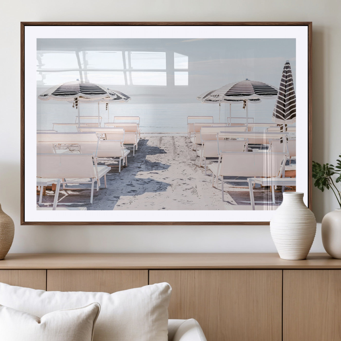 A serene minimalist beach scene featuring striped umbrellas, soft pastel sand, and an elegant lounge setup, creating a tranquil and stylish coastal retreat.