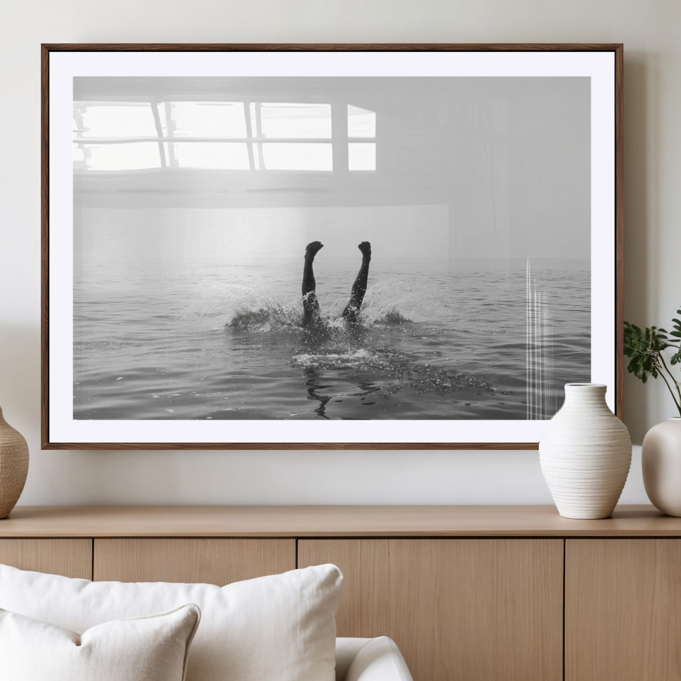 A black and white minimalist water scene capturing a playful splash as a swimmer dives upside down, creating a carefree and artistic aquatic aesthetic.