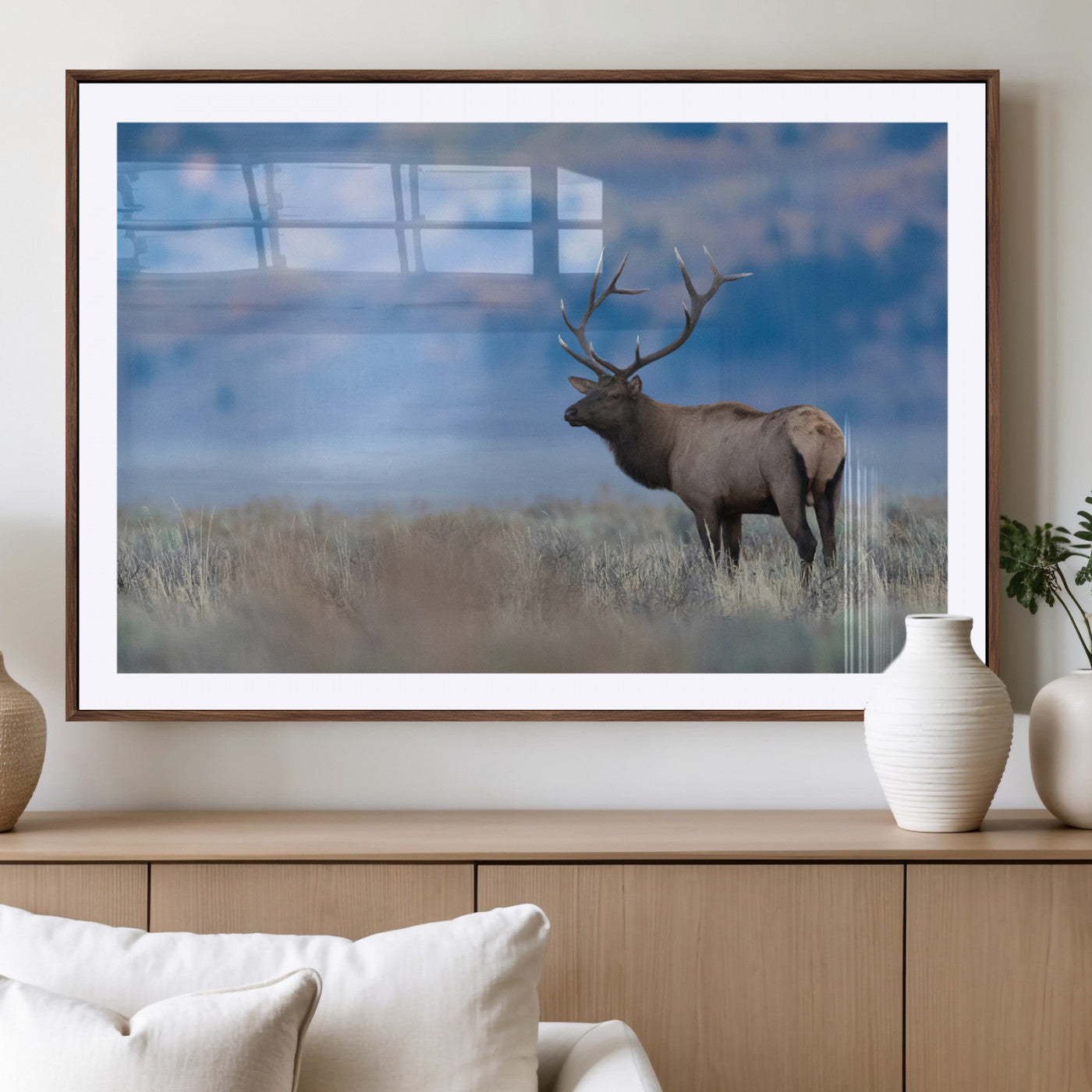 Elk with large antlers standing in open field, mountains blurred in background, perfect for rustic cabin or lodge-style decor.