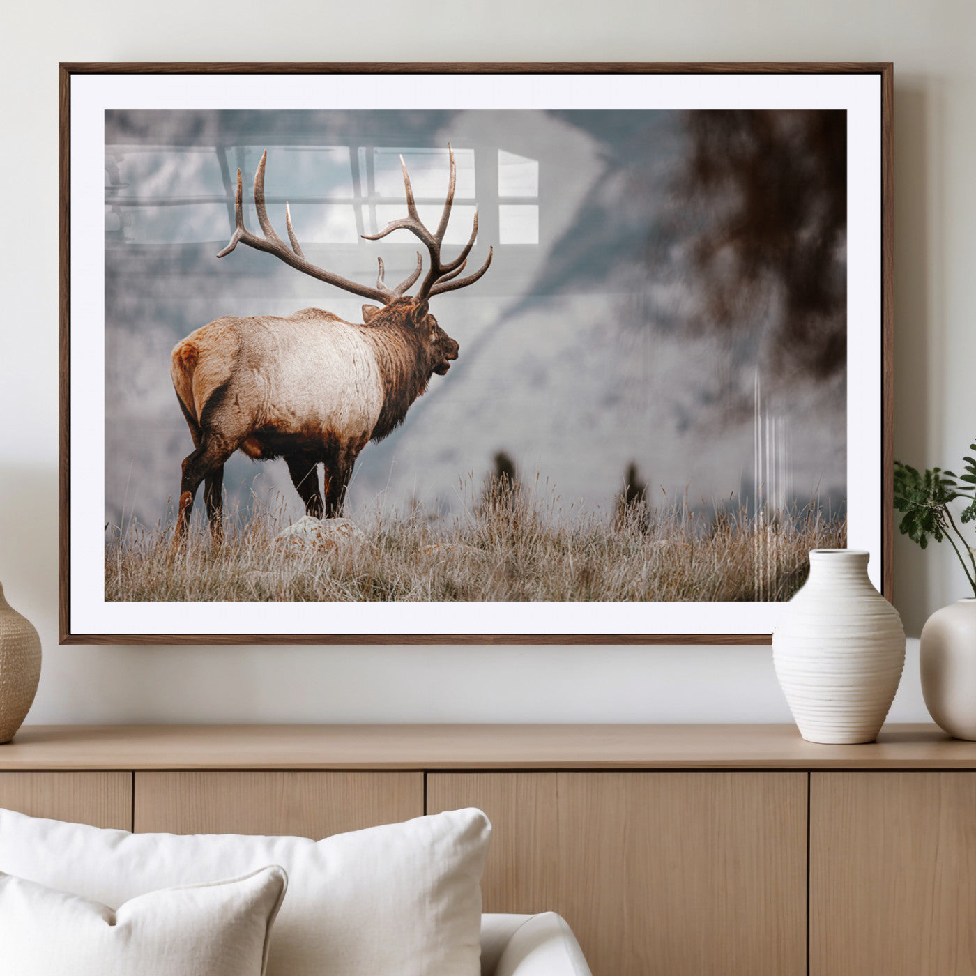 Majestic elk with large antlers standing in grass with snowy mountains in background, perfect for rustic cabin or lodge style decor.