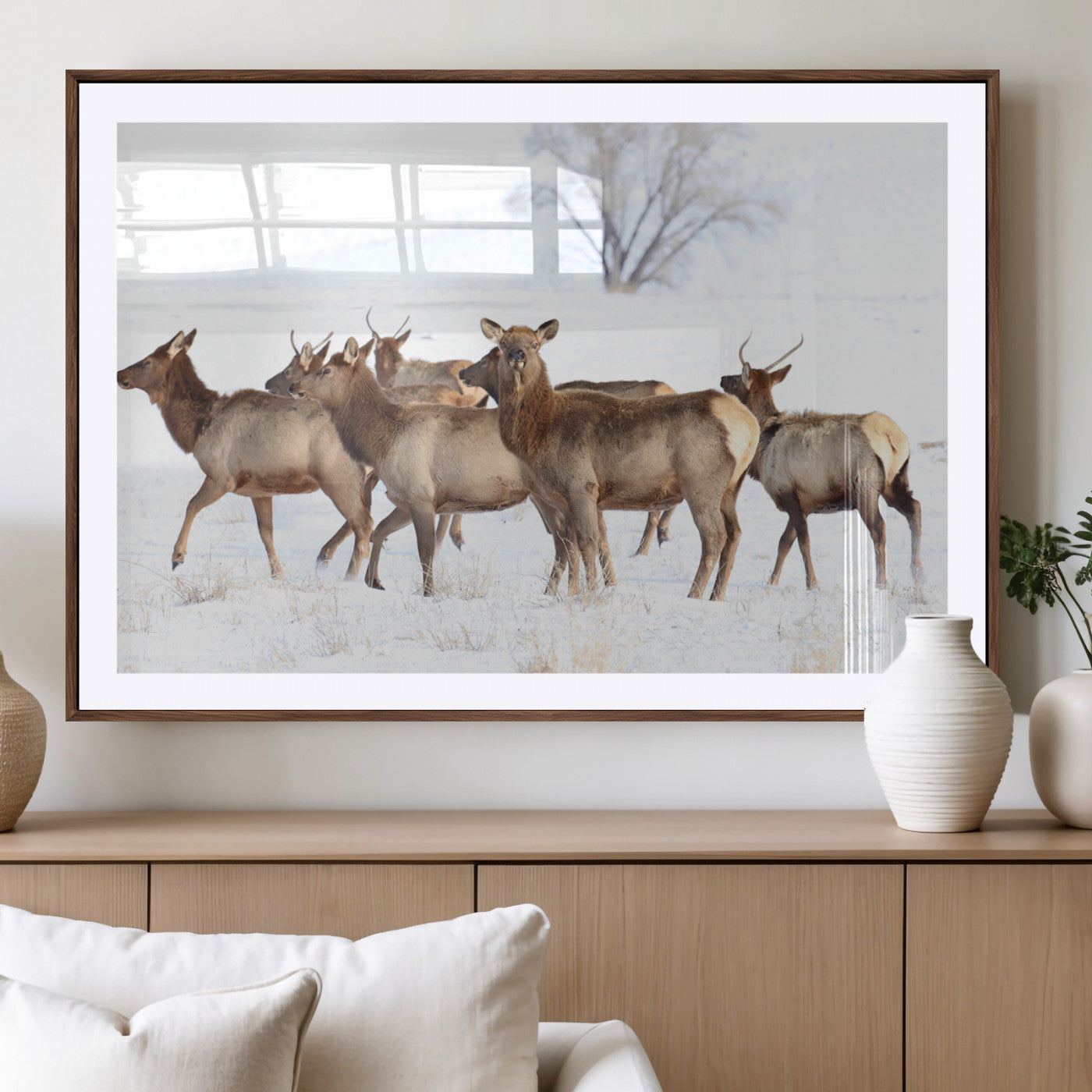 A group of elk standing on snowy terrain with a tree in the background, perfect for rustic or lodge-style winter wall decor.